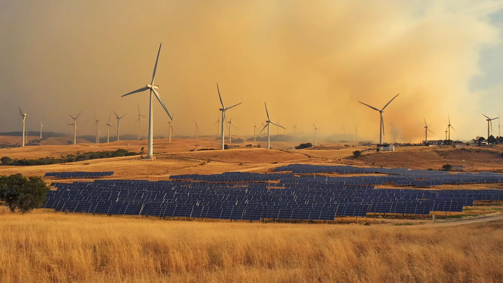 Wind turbines and a solar farm on dry Australian hills under a bushfire smoke haze.