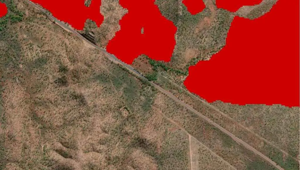 The algorithm's red overlay mapping a fire scar boundary precisely where it meets a clump of trees along the Stuart Highway.