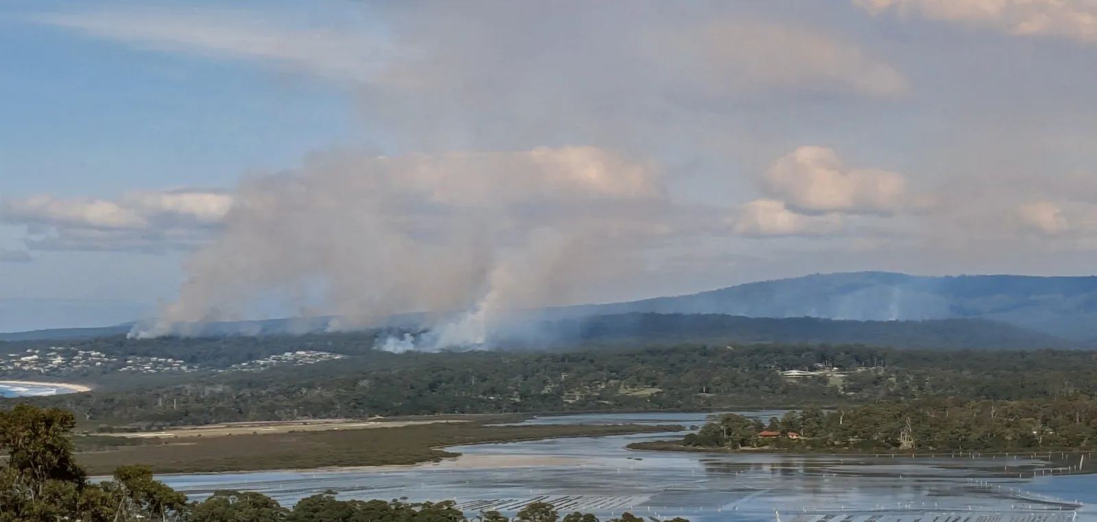 Low smoke drifting across the inlet and forested ridges of the Far South Coast during the autumn 2026 hazard reduction burns.